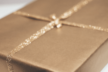 Unisex gift wrapped in plain paper with gold ribbon